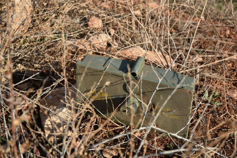 A Russian mine lies hidden in a thorny bush on the dusty Aleppo ground