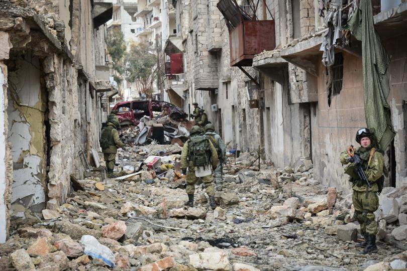 Russian soldiers pick through the rubble on this Aleppo street, which has been severely damaged in the bombardment, while the remains of a burnt-out car stand in the background